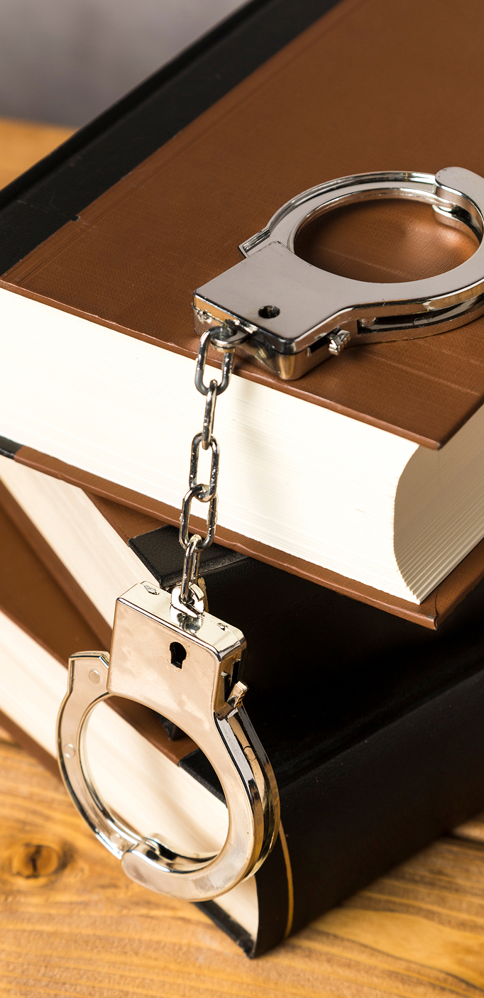 Legal defence for criminal charges in the UK Handcuffs on law books representing criminal defence for Poles in the UK