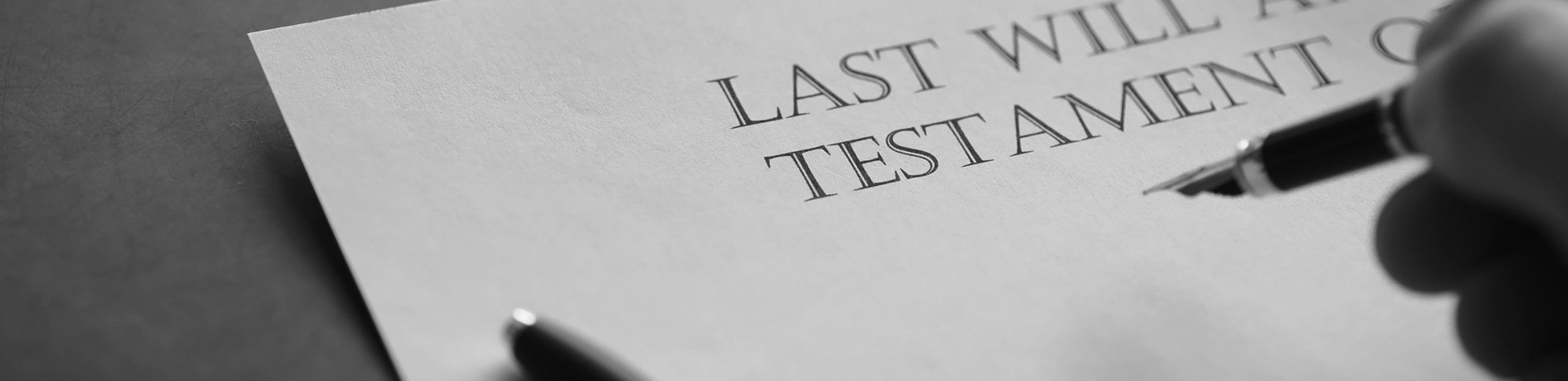 Testament i dłoń z długopisem – przygotowanie dokumentów spadkowych